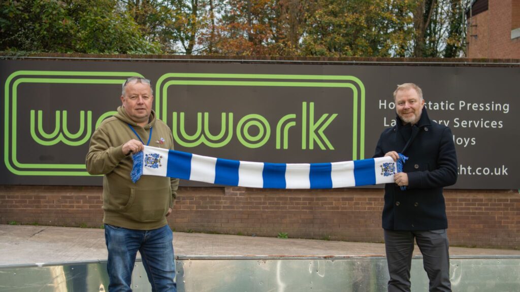 Simeon Collins in front of the new sponsor board for Wallwork Group